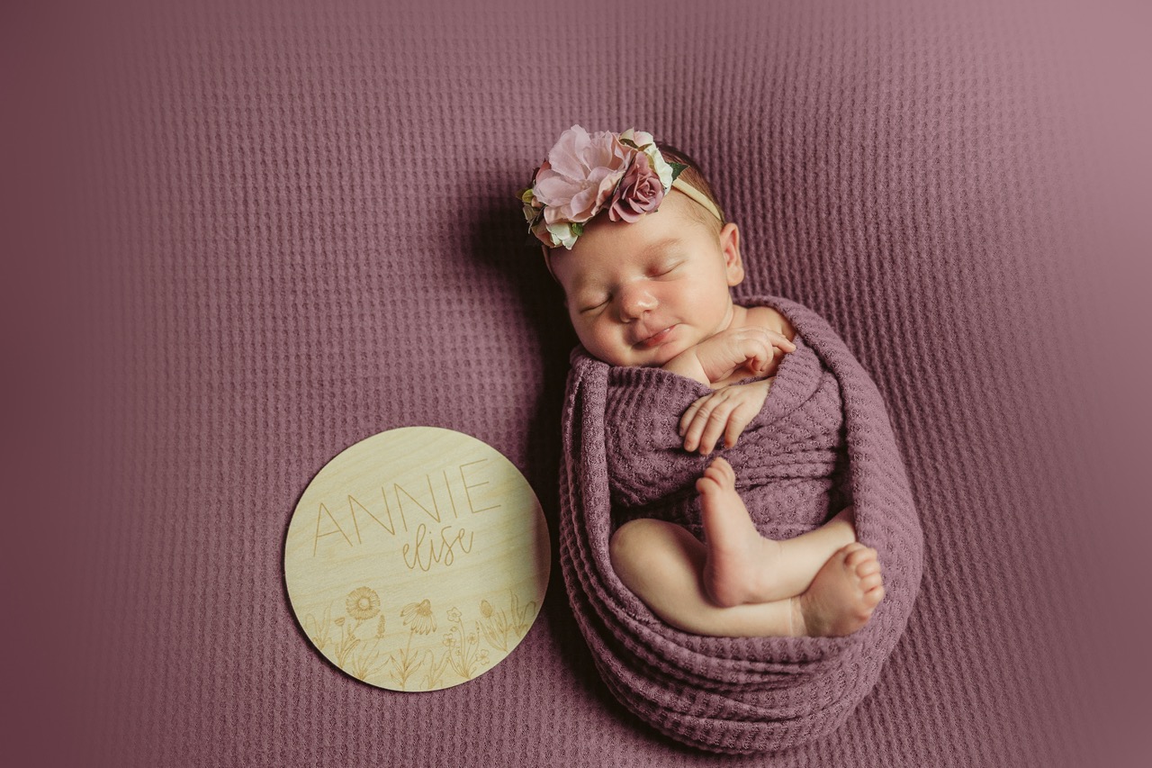 studio newborn session of baby on purple backdrop